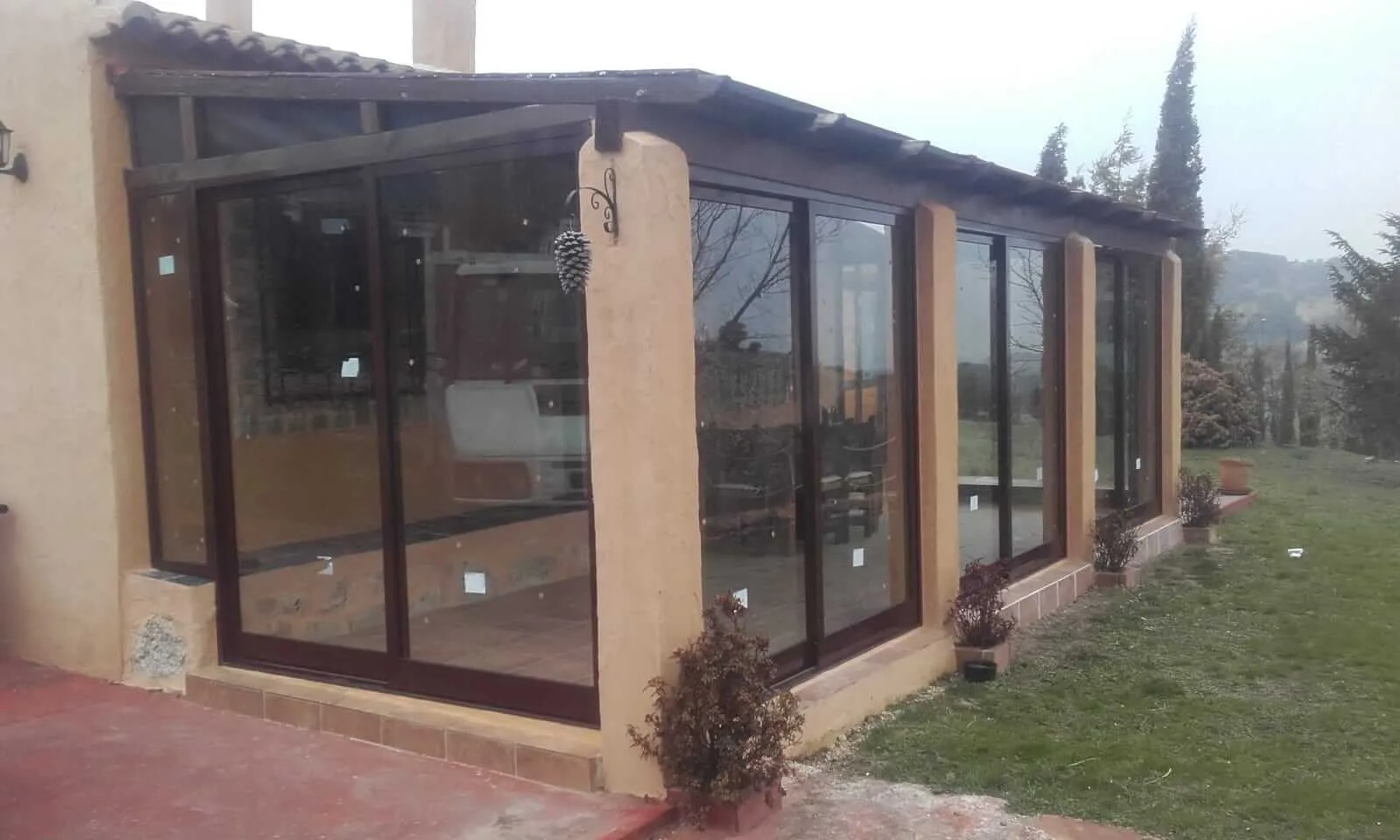 Cerramiento de terraza con estructura de aluminio marrón y cristales correderos, realizado por Carpintería Metálica Toni en San Pedro, Albacete