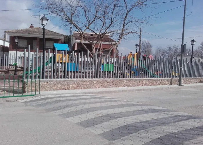 Cerramiento metálico para parque infantil fabricado por Carpintería Metálica Toni en San Pedro, Albacete, con diseño moderno en varilla redonda de diferentes alturas sobre muro de piedra.