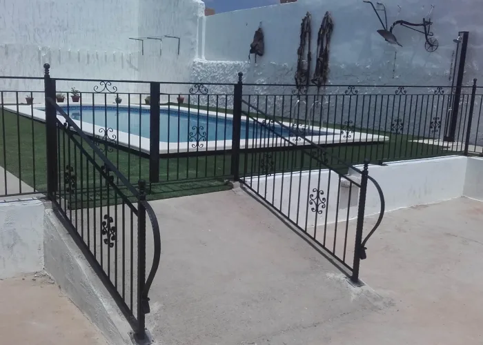 Cerramiento metálico decorativo en color negro para piscina, con barandillas y portones de acceso, fabricado por Carpintería Metálica Toni en San Pedro, Albacete.
