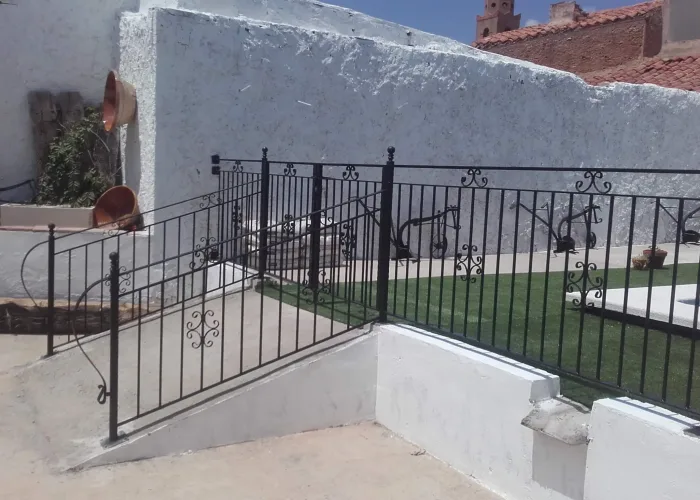 Cerramiento metálico decorativo en color negro para piscina, con barandillas y portones de acceso, fabricado por Carpintería Metálica Toni en San Pedro, Albacete.