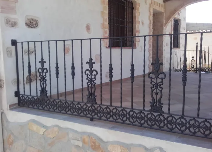 Barandilla de forja artística en color negro instalada en porche de vivienda, con detalles ornamentales y acabado clásico, fabricada por Carpintería Metálica Toni en San Pedro, Albacete.