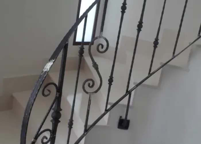 Barandilla de hierro forjado en escalera interior de diseño curvo, con pasamanos artesanal y barrotes decorativos, realizada por Carpintería Metálica Toni en San Pedro, Albacete.