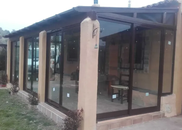 Cerramiento de terraza con estructura de aluminio marrón y paneles de vidrio, realizado por Carpintería Metálica Toni en una vivienda rural en San Pedro, Albacete
