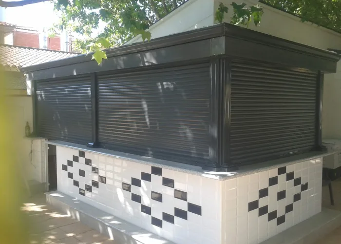 Cierre de bar exterior con persianas enrollables de aluminio en color negro, instalado por Carpintería Metálica Toni en San Pedro, Albacete