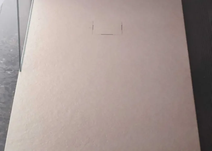 Plato de ducha texturizado en tono beige claro con desagüe centrado, instalación realizada por Carpintería Metálica Toni en San Pedro, Albacete.