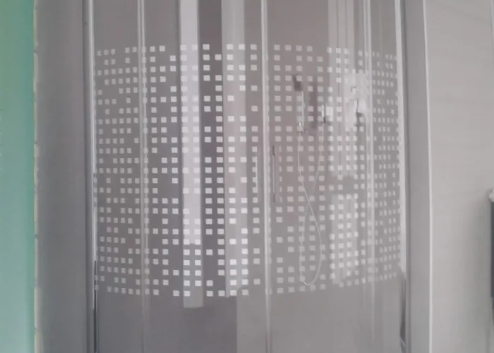 Mampara de ducha curva con cristal decorado y serigrafía de cuadros, instalada con plato semicircular en baño moderno, trabajo realizado por Carpintería Metálica Toni en San Pedro, Albacete.