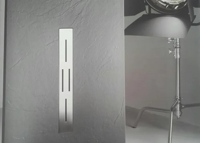 Plato de ducha de textura pizarra en color gris antracita con rejilla central vertical en acero inoxidable, diseño moderno presentado por Carpintería Metálica Toni en San Pedro, Albacete.