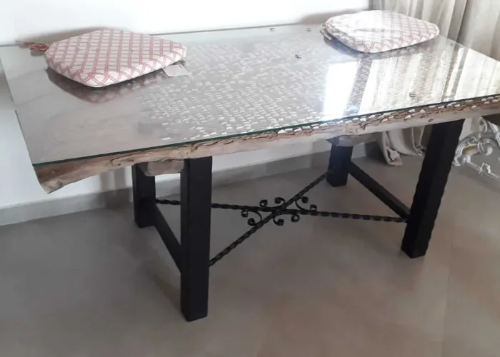 Mesa rústica con estructura de hierro forjado y sobre de madera natural protegido por cristal templado, realizada por Carpintería Metálica Toni en San Pedro (Albacete). Un diseño artesanal que combina robustez, elegancia y materiales nobles para espacios interiores con carácter.