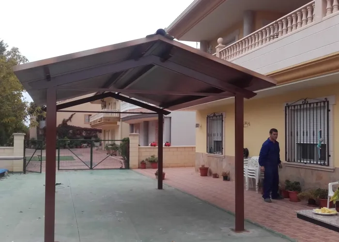 Pérgola metálica instalada junto a piscina con cubierta tipo panel teja y estructura marrón, fabricada por Carpintería Metálica Toni en San Pedro, Albacete