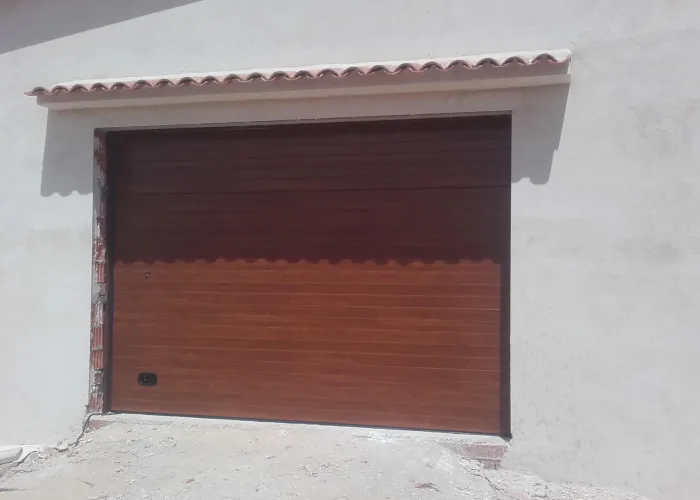 Puerta seccional automática de garaje en panel sándwich con acabado imitación madera, fabricada por Carpintería Metálica Toni en San Pedro, Albacete