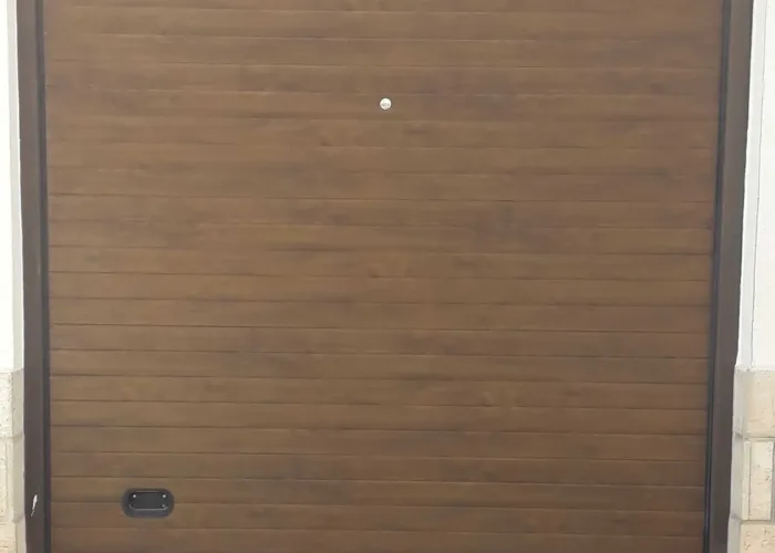 Puerta seccional automática en panel sándwich con acabado imitación madera, fabricada por Carpintería Metálica Toni en San Pedro, Albacete