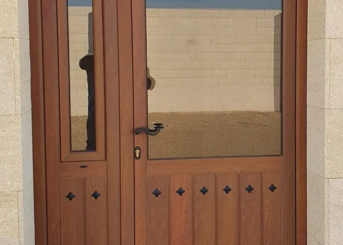 Puerta de entrada exterior en aluminio imitación madera con detalles decorativos, fabricada por Carpintería Metálica Toni en Albacete