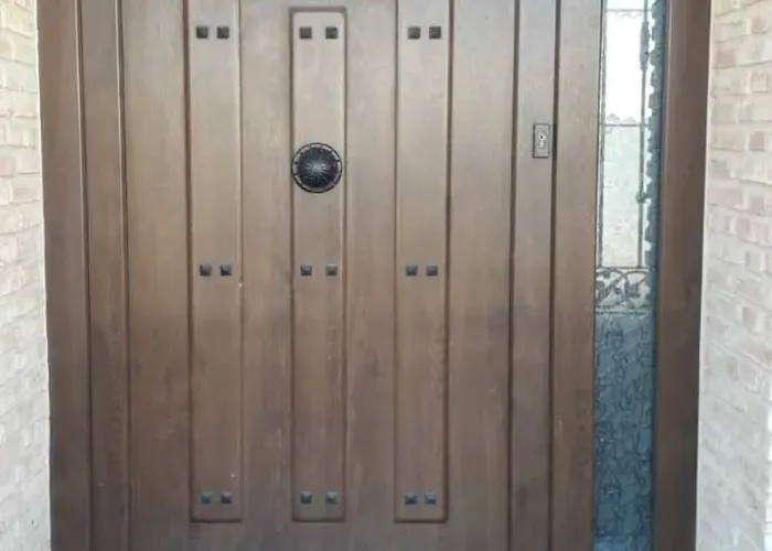 Puerta de entrada de aluminio imitación madera con cristal lateral y reja decorativa central, fabricada a medida por Carpintería Metálica Toni en Albacete