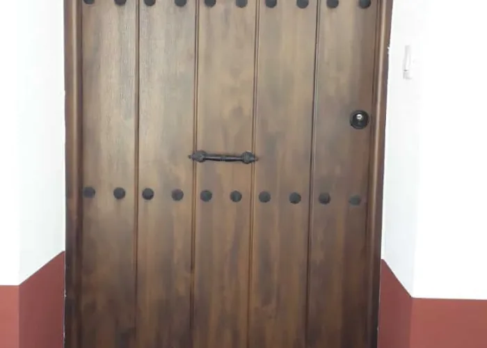 Puerta de entrada de aluminio en acabado imitación madera con clavos decorativos, fabricada por Carpintería Metálica Toni en San Pedro, Albacete