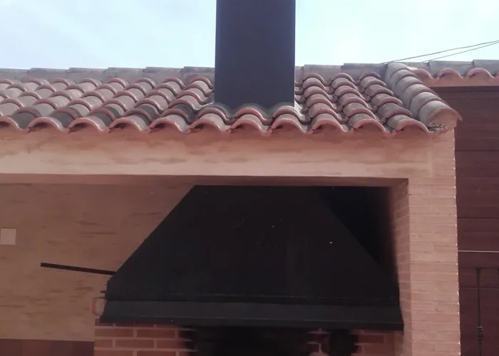 Horno de leña de obra con campana metálica decorativa y puerta de hierro, fabricado por Carpintería Metálica Toni en San Pedro, Albacete