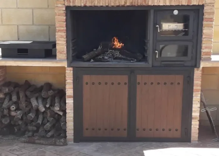 Barbacoa de obra con horno metálico y puertas de forja imitación madera, diseñada por Carpintería Metálica Toni en San Pedro, Albacete