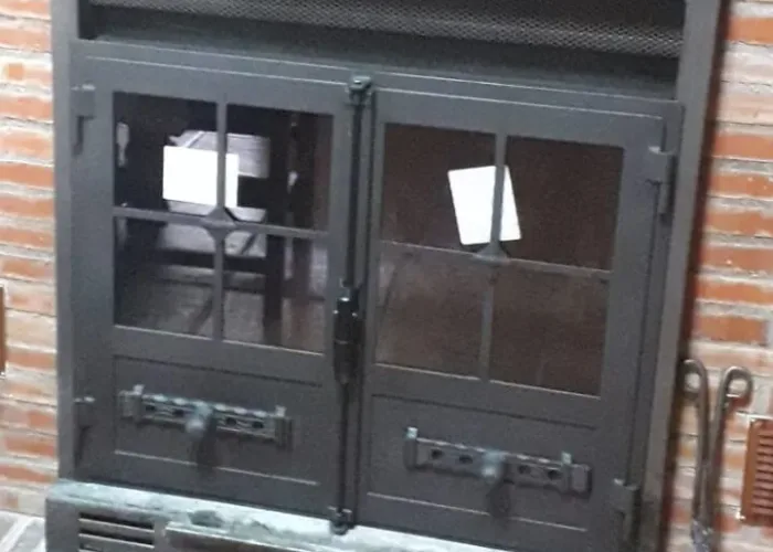 Puerta metálica de chimenea empotrada con doble hoja de cristal y sistema de ventilación, fabricada por Carpintería Metálica Toni en San Pedro, Albacete
