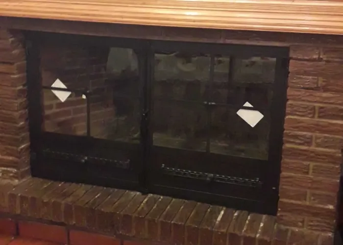 Puerta de chimenea empotrada con doble hoja acristalada en marco metálico, fabricada por Carpintería Metálica Toni en San Pedro, Albacete