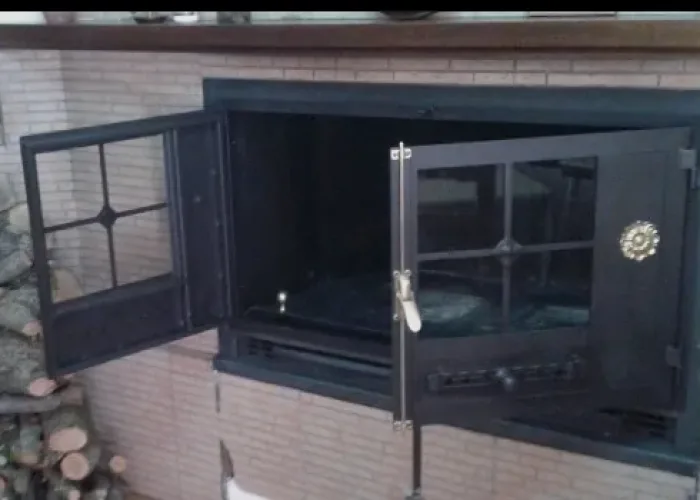 Puerta de chimenea metálica de doble hoja abatible con cristal y tirador decorativo, fabricada por Carpintería Metálica Toni en San Pedro, Albacete