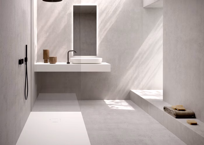 Baño minimalista con plato de ducha extraplano blanco de gran formato y grifería negra empotrada. Diseño elegante con mampara fija de vidrio y lavabo suspendido. Proyecto fabricado por Carpintería Metálica Toni en San Pedro, Albacete.