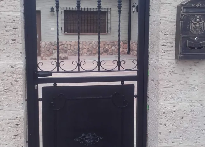 Puerta de acceso peatonal de forja con diseño clásico y remates ornamentales, fabricada por Carpintería Metálica Toni en San Pedro (Albacete). Ideal para cerramientos residenciales que buscan combinar seguridad y un estilo tradicional elegante.